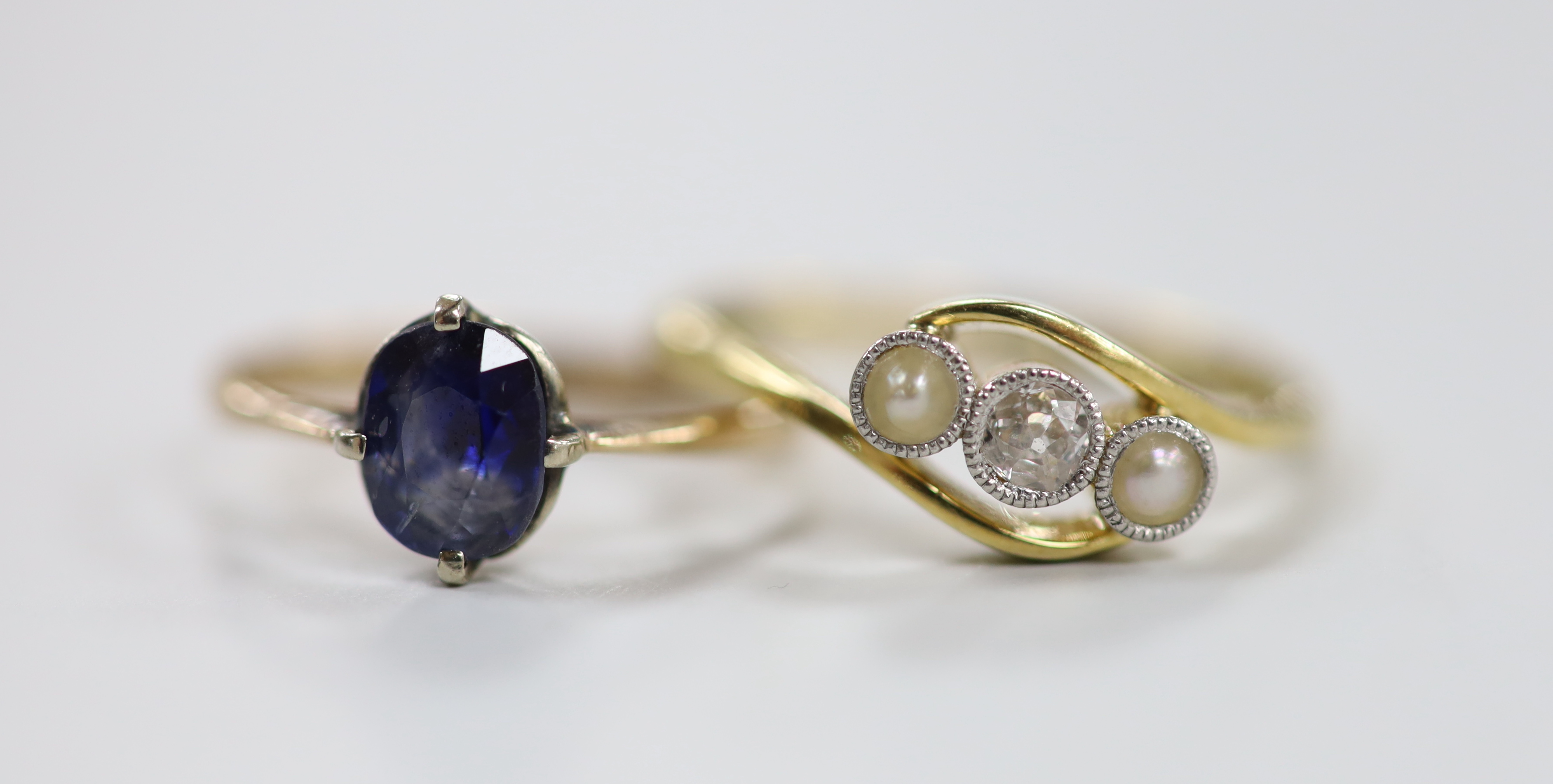 An 18ct and plat, singe stone diamond and two stone split pearl set crossover ring, size Q and a yellow metal and single stone sapphire set ring, gross weight 4.7 grams.